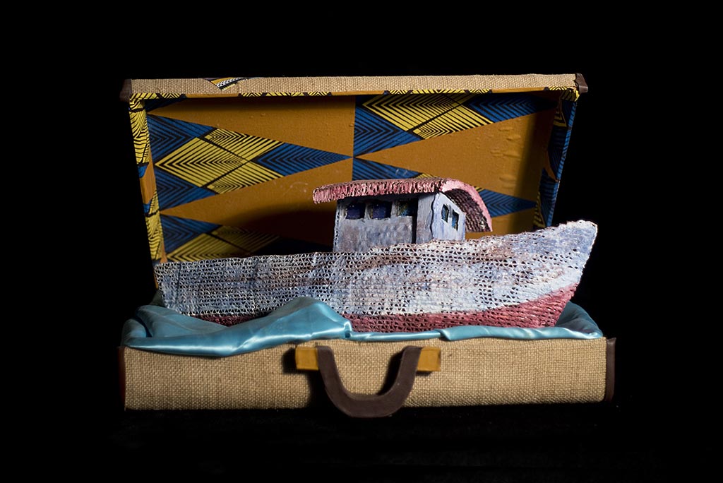 'A boat made of a very loose knit fabric or mesh sits inside a suitcase'